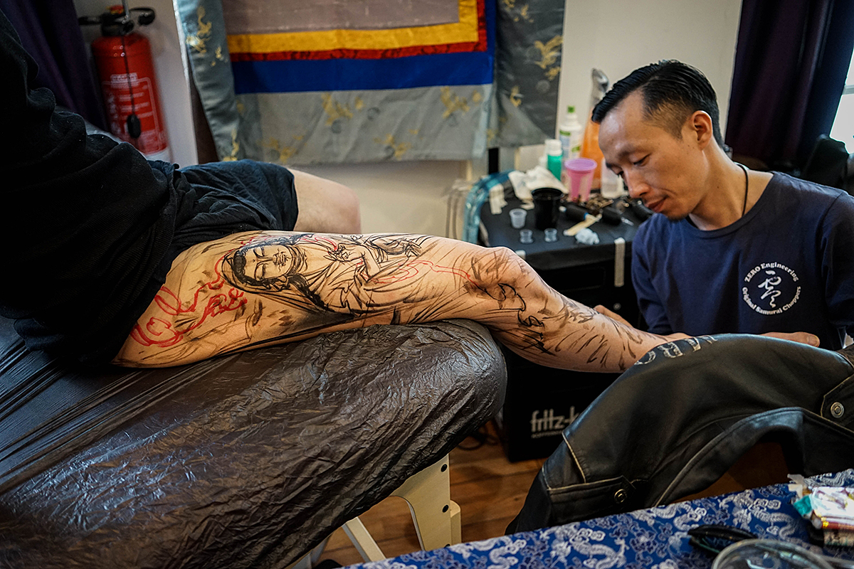 Dong Dong bei der Arbeit am Bein eines Kunden auf dem Spiekerooger Tattoo-Treff
